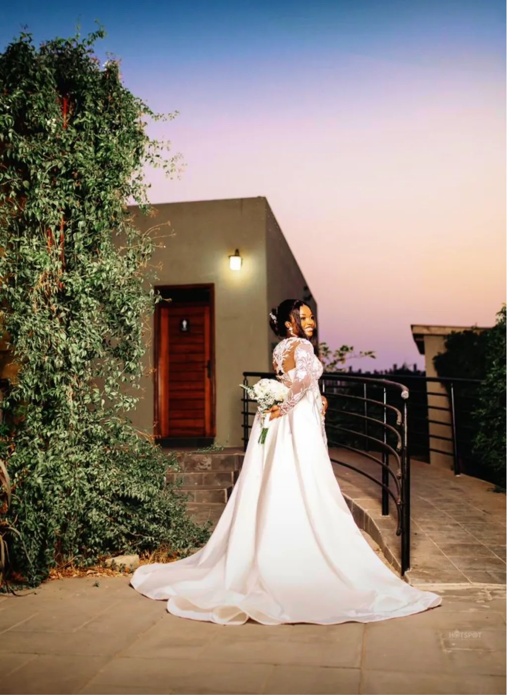 Bride in an elegant white gown with a long train at the venue at dusk