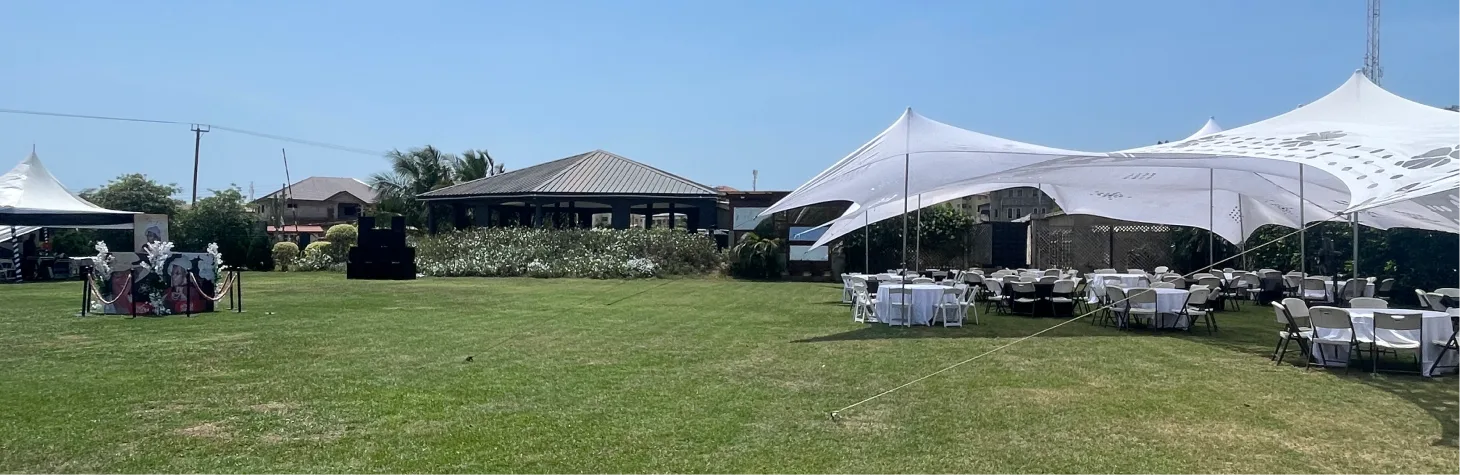 Guests seated under white umbrellas on the green lawn